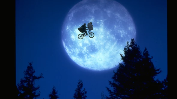 E.T. and Elliott are soaring in the night on a bicycle, past a giant moon