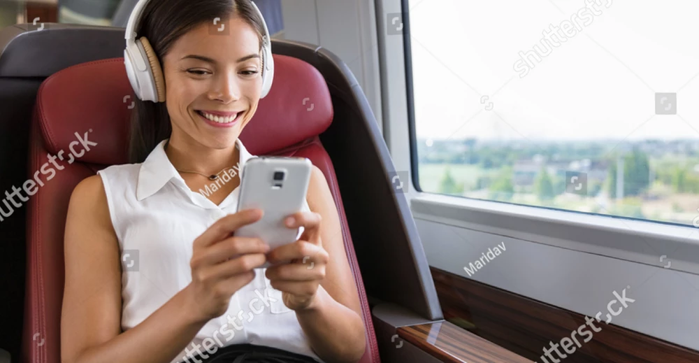 Girl sitting on the train with headphones looking at her mobile