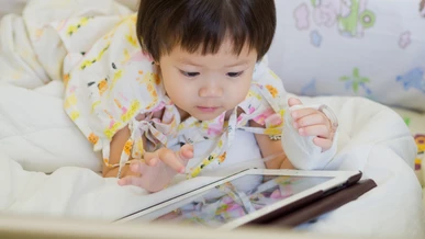 A little girl with a broken wrist is watching a film on her tablet on her hospital bed