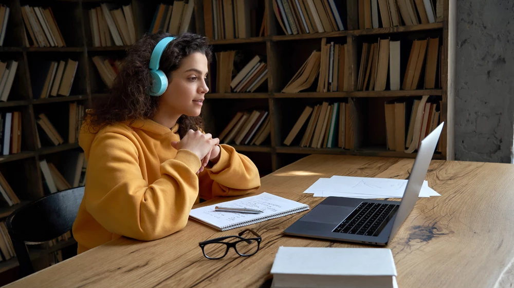 A student is watching a film on her laptop in the library