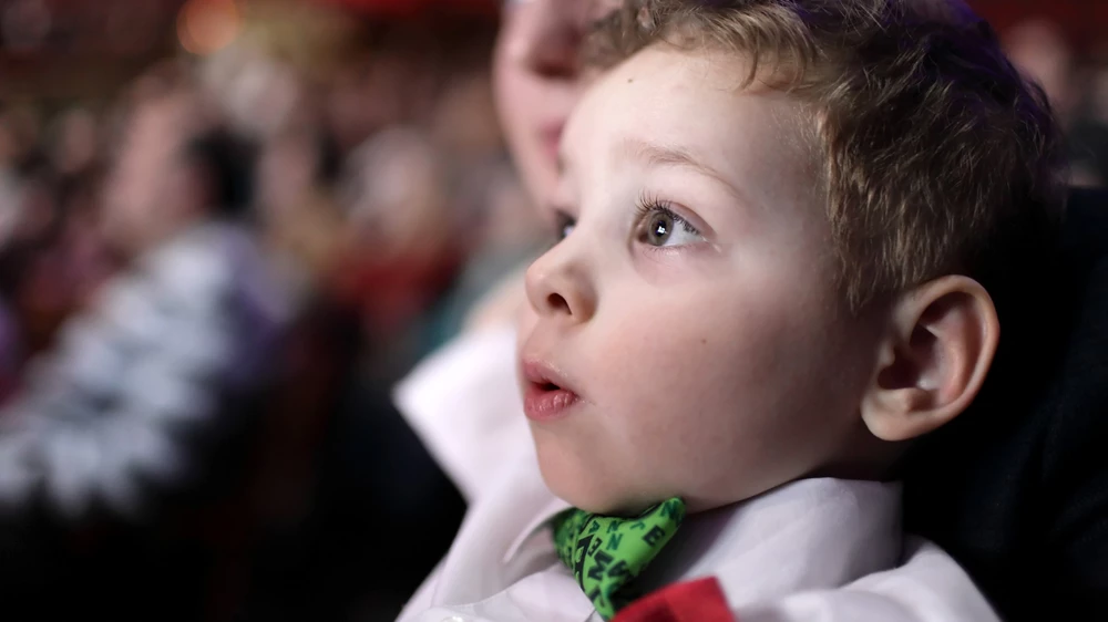 A little boy is enjoying a film screening in an audience
