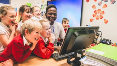 A teacher and his pupils are watching a funny film on a screen