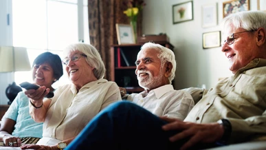 Care home residents are watching a film on TV and laughing together